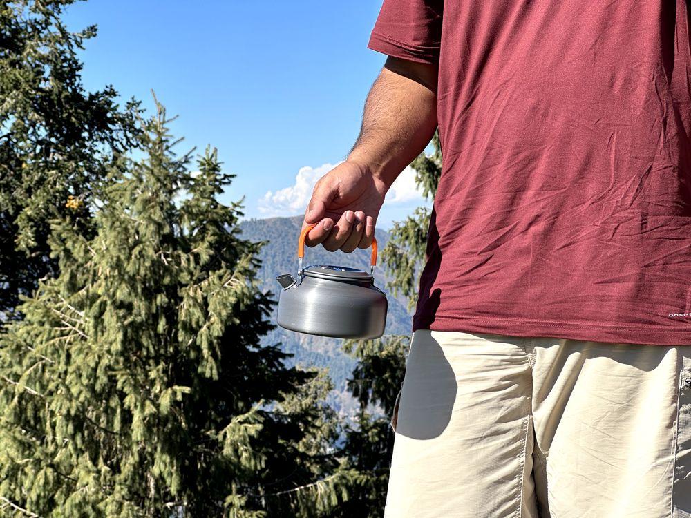 Holding a camping kettle from handle while outdoor