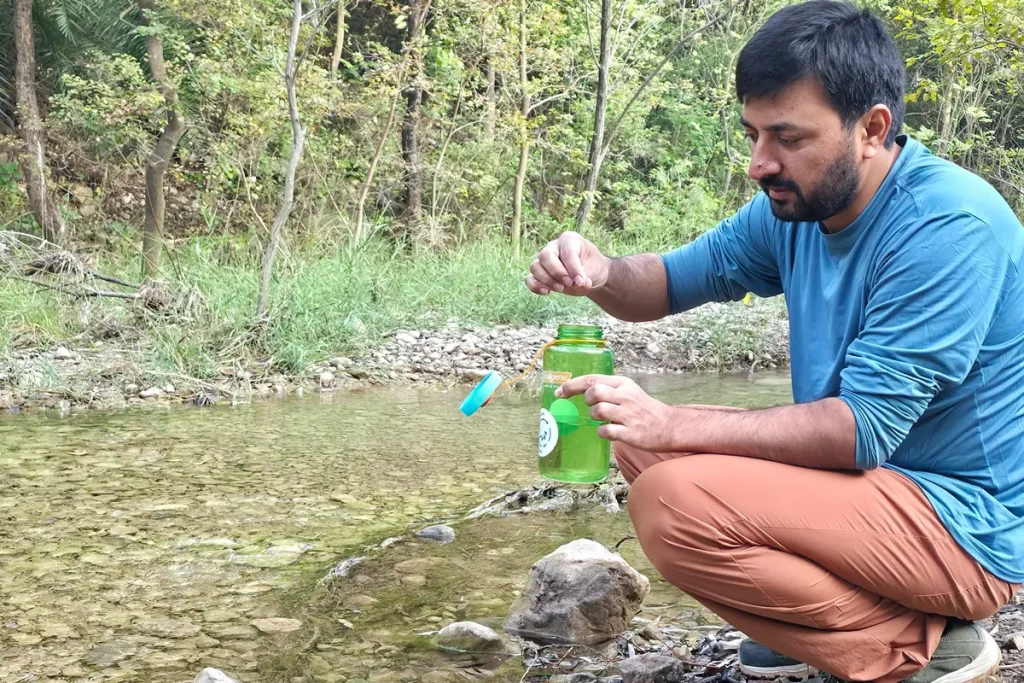 Adding a water purification tablet to a Nalgene Wide Mouth bottle beside a stream