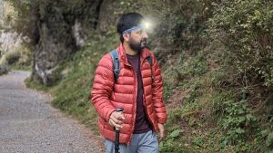 Hiker wearing a headlamp and using a trekking pole on a trail